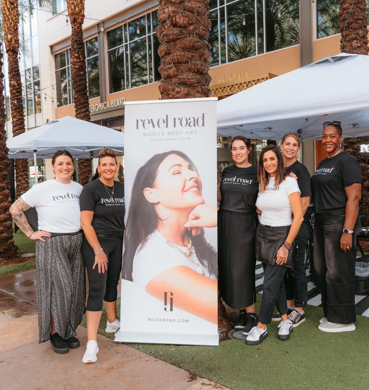 The Revel Road team beside their branded pull-up banner and styling tent at Scottsdale Quarter