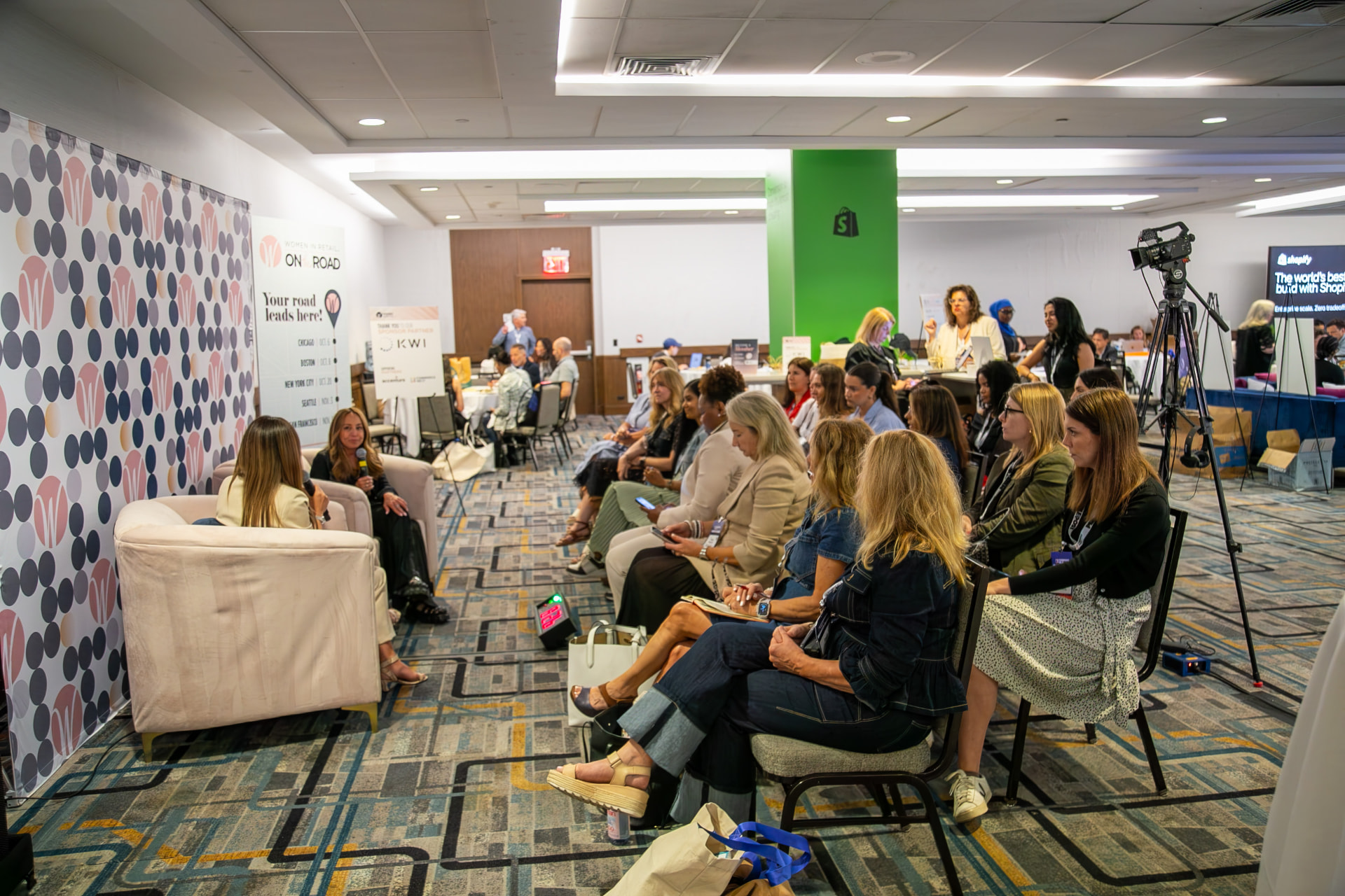 A Women in Retail Leadership conversation on stage in front of the Women in Retail on Road backdrop at CommerceNext