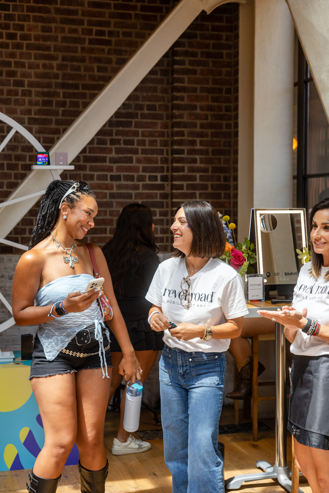 Guest with glitter styling posing with Revel Road artists at the Lollapalooza rooftop activation in Chicago