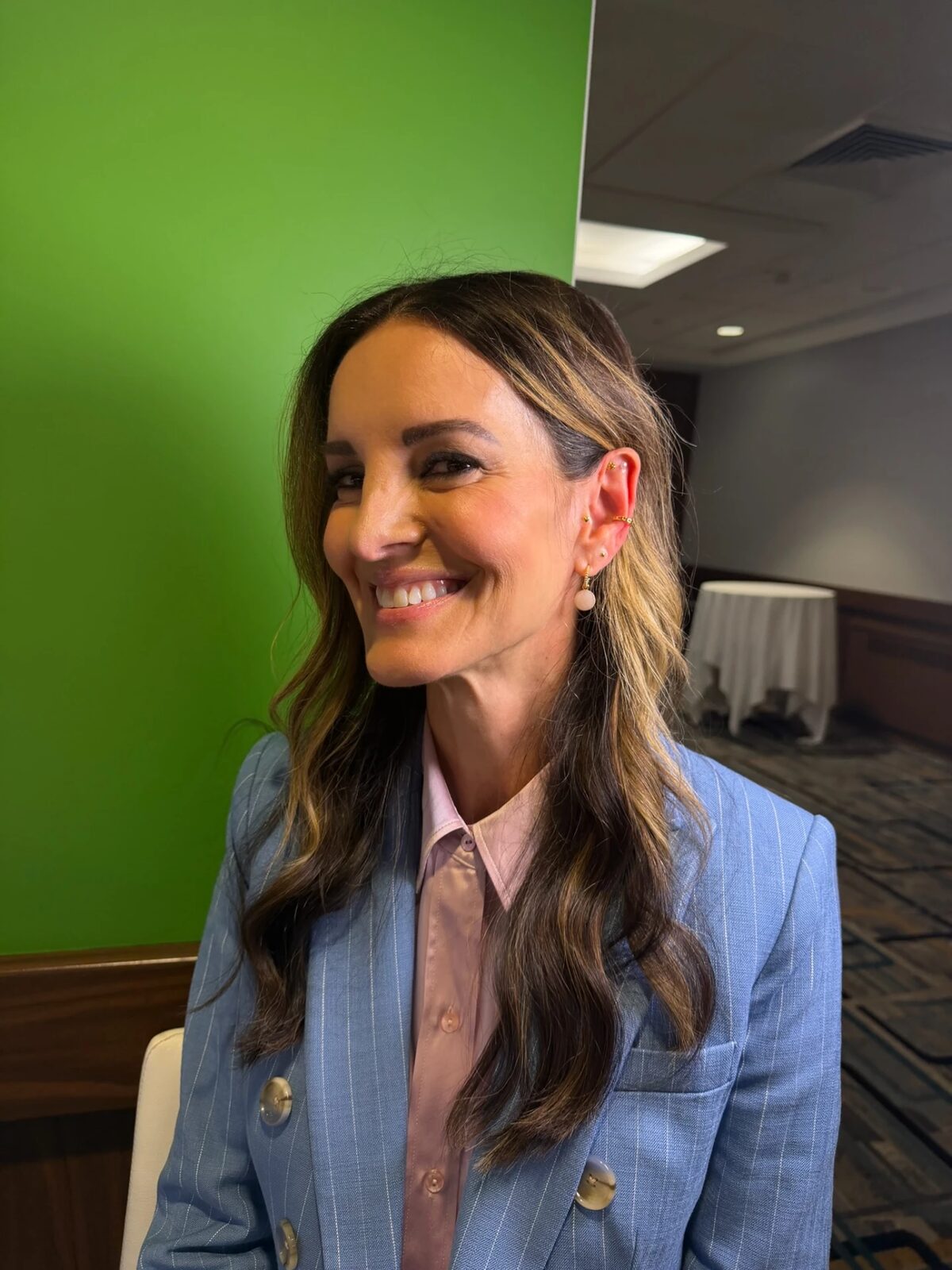 Attendee in a blue pinstripe blazer smiling with a gold Revelmarks stack