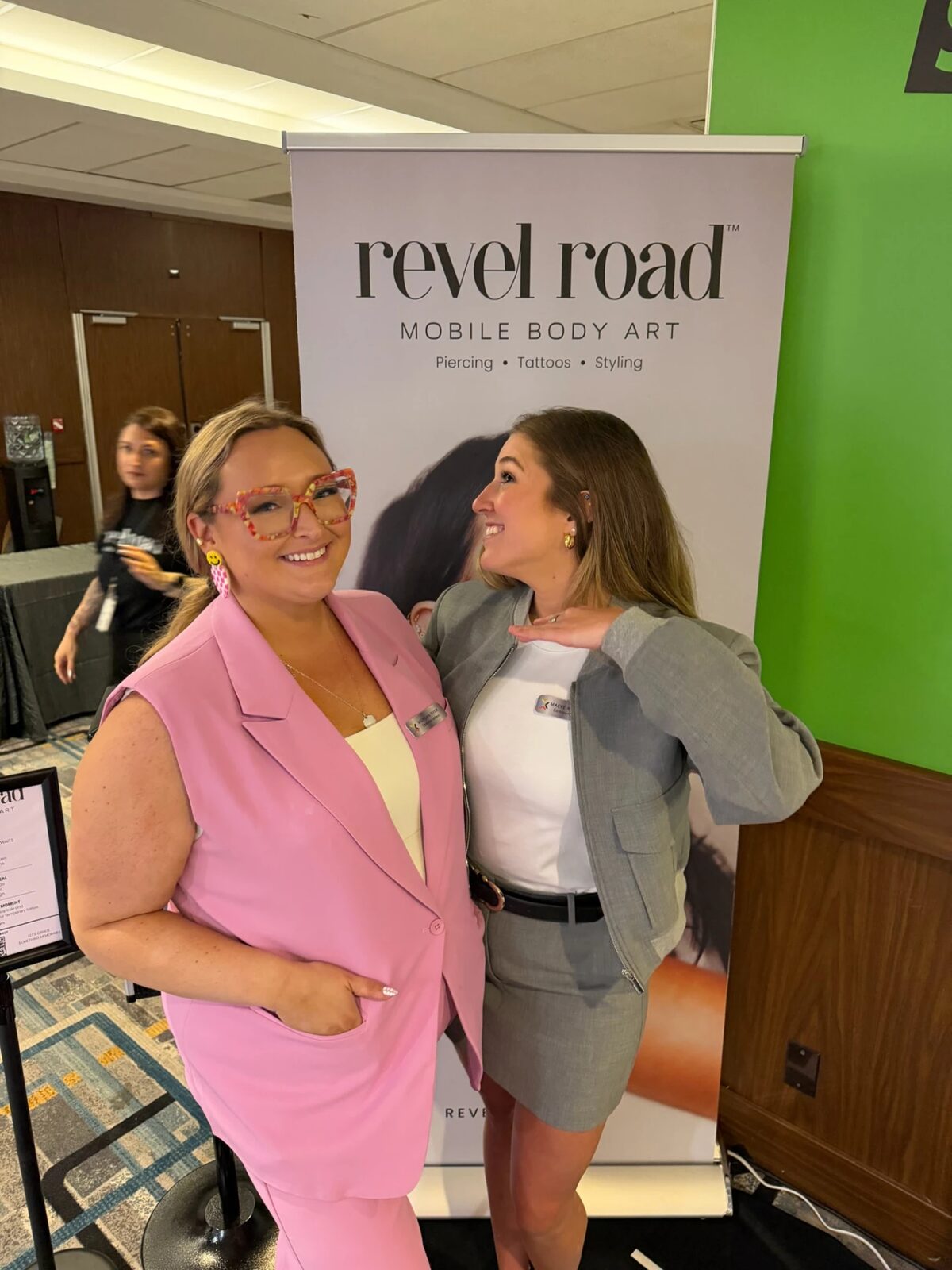 Two attendees posing in front of a Revel Road banner at the CommerceNext Growth Show