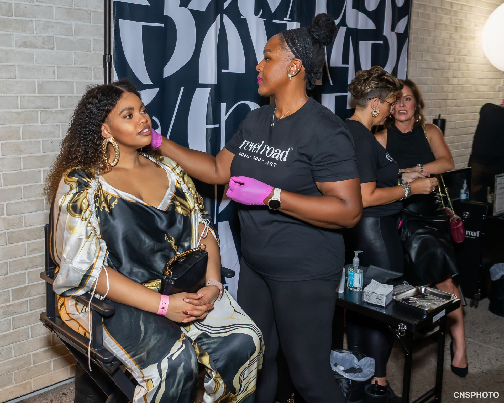 Revel Road Artist styling a guest in a gold and black satin set at the Scottsdale Fashion Week Kickoff