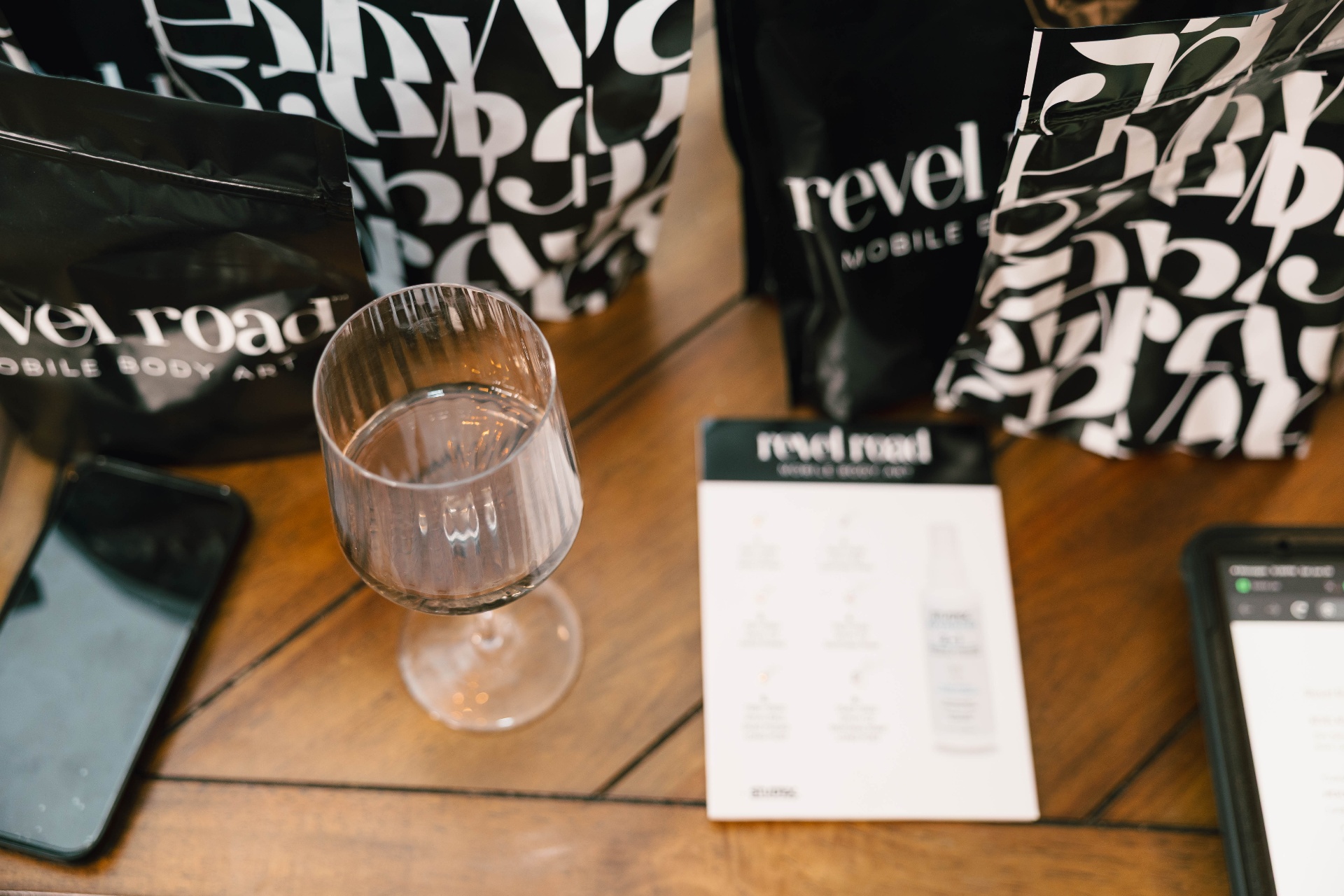 Revel Road branded pouches styled on a table with wine glass