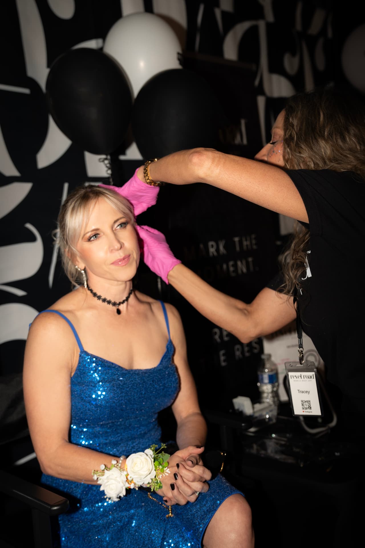 Revel Road artist applying glitter to a guest in a blue sequin dress at the Earlybirds Phoenix party